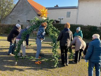 Zahlreiche Helfer beim weihnachtlichen Schmücken des Dorfbrunnens 