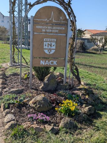 Ortseingangsschild mit Blumenbeet